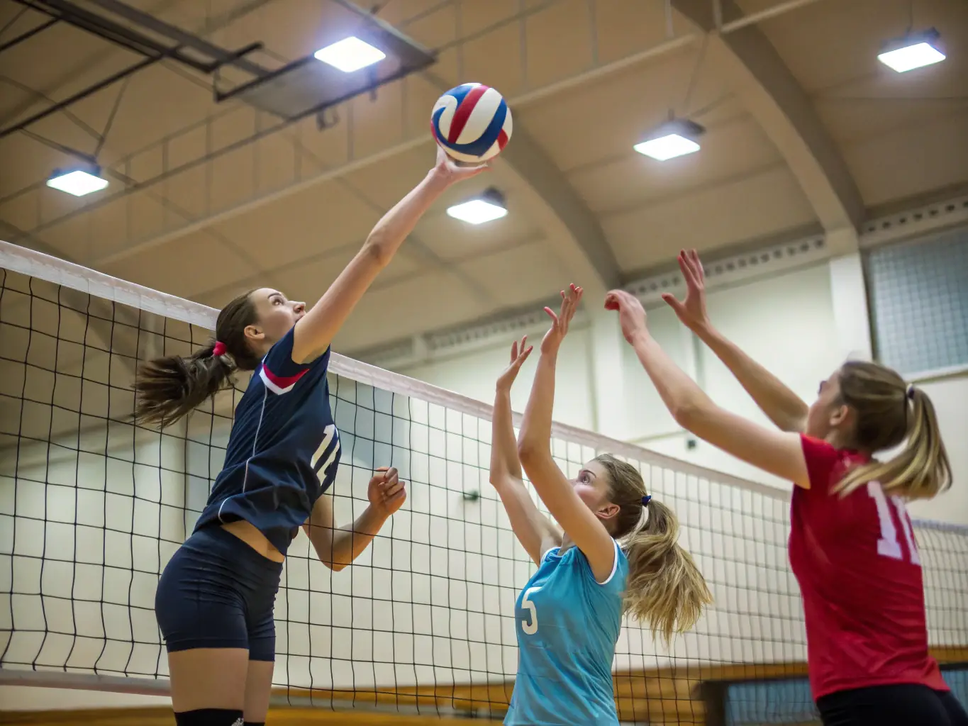 A photograph of adult volleyball players participating in a competitive match, showcasing the intensity and camaraderie of the sport, taken during an evening game.